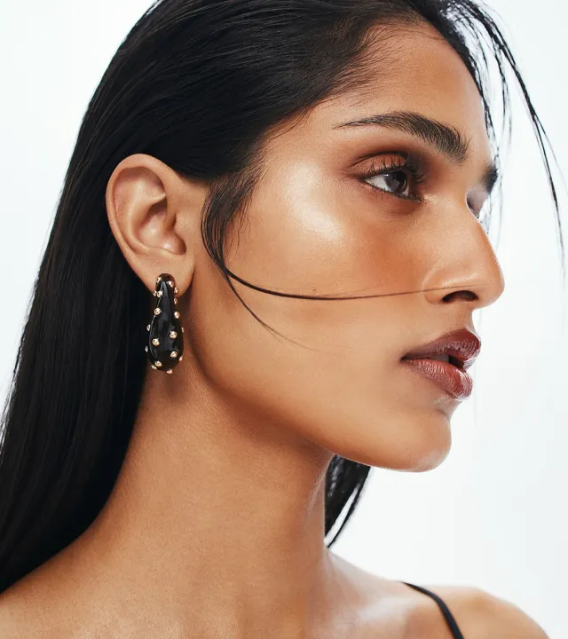 A side profile photo of a model with bronzed and highlighted skin