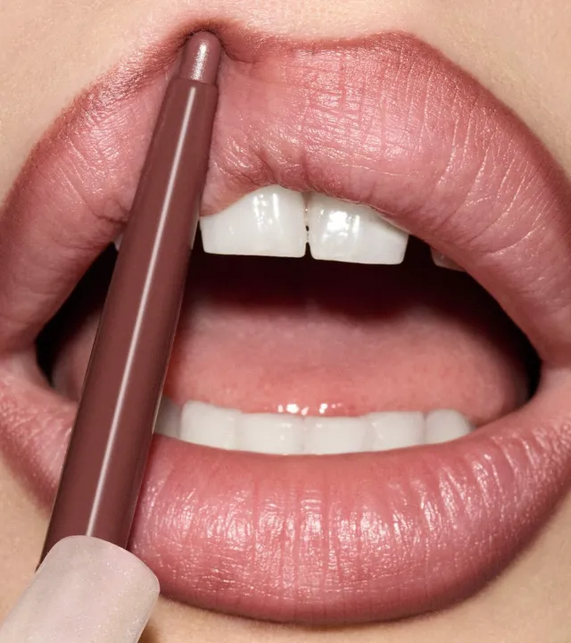 A zoomed-in shot of a woman's lip with a brown lip liner applied