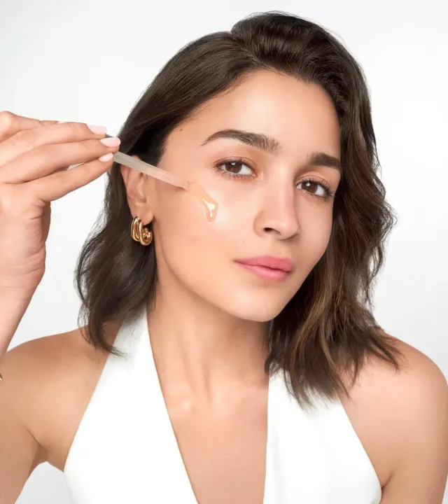 Alia Bhatt applying the best glycolic acid serum on her face using a dropper