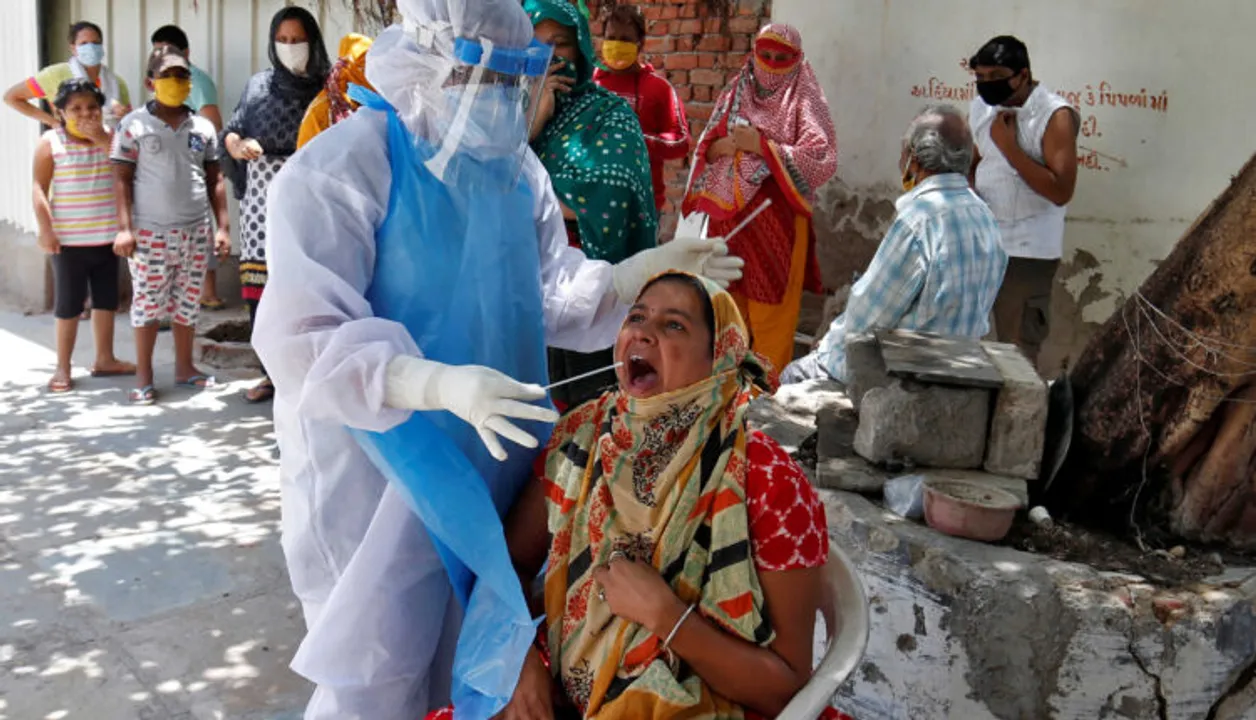  A woman reacts as a healthcare worker wearing a protective gear takes a swab to test for the coronavirus disease (COVID-19) at a residential area in Ahmedabad, India, May 22, 2020. REUTERS/Amit Dave?? 