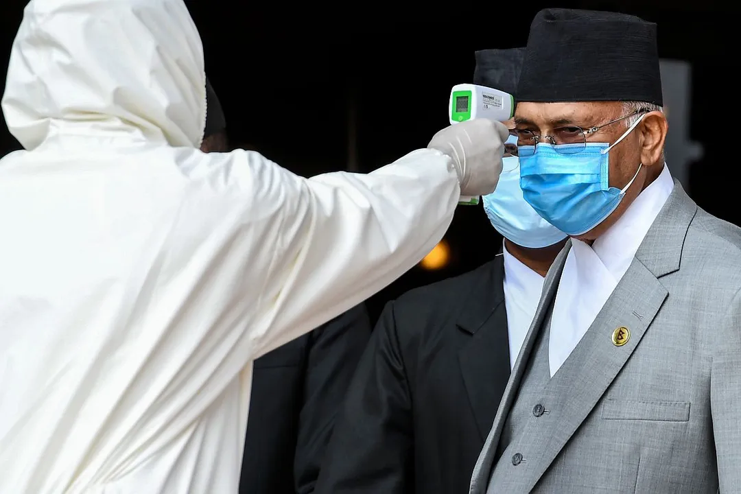  A health worker in protective gear checks the body temperature of Nepal's Prime Minister KP Sharma Oli (R) as he arrives at the parliament to present the new government's programme for the fiscal year 2020/2021 in Kathmandu on May 15, 2020. (Photo by PRAKASH MATHEMA / AFP) 