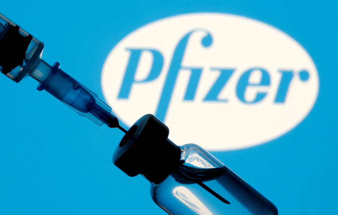  FILE PHOTO: A vial and syringe are seen in front of a displayed Pfizer logo in this illustration taken January 11, 2021. REUTERS/Dado Ruvic/Illustration 