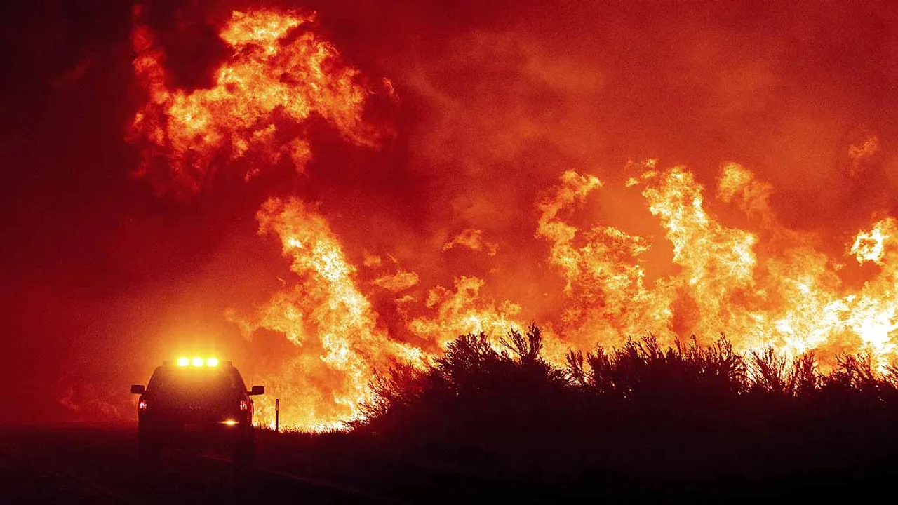  Flames leap above a fire vehicle as the Dixie Fire jumps Highway 395 south of Janesville in Lassen County, Calif., on Monday, Aug. 16, 2021. Critical fire weather throughout the region threatens to spread multiple wildfires burning in Northern California. (AP Photo/Noah Berger) 