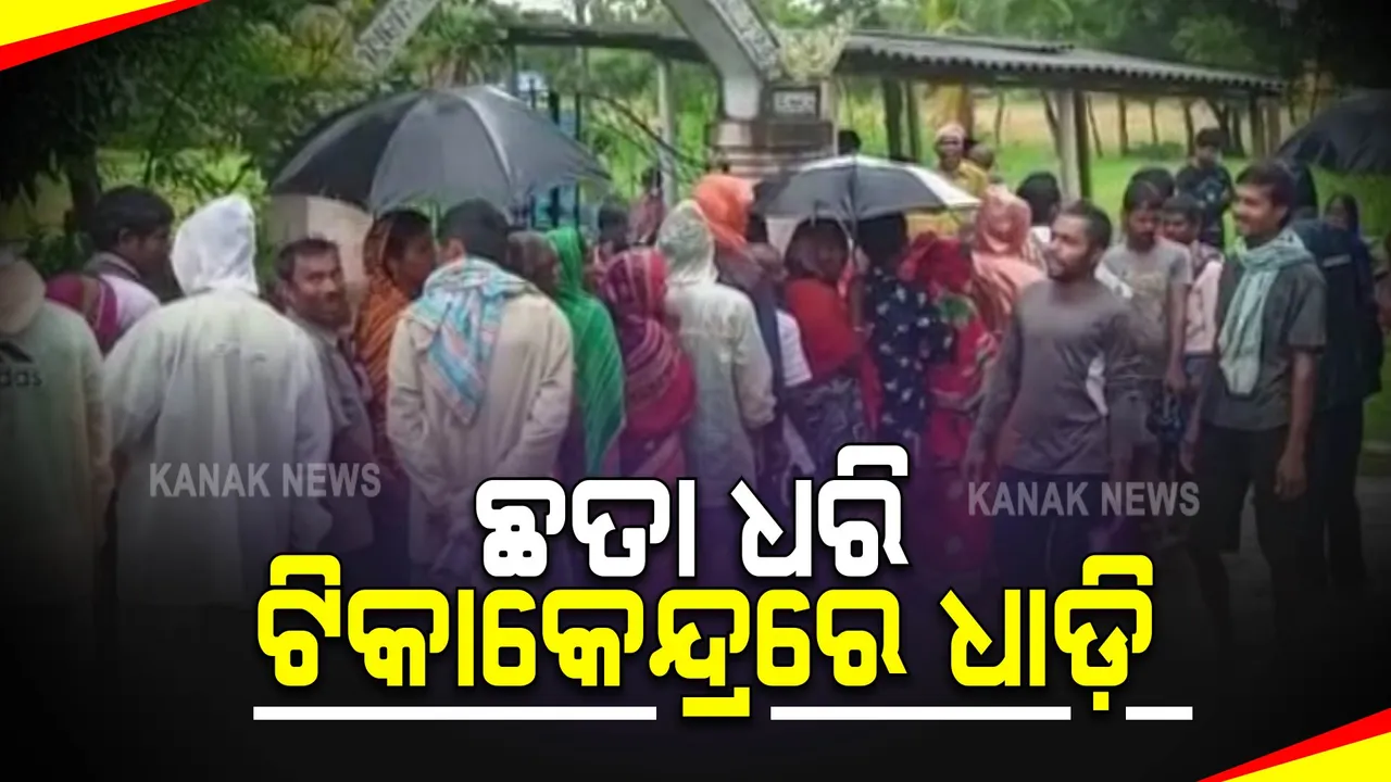  ପ୍ରବଳ ବର୍ଷାରେ ଛତା ଧରି ଟିକାକେନ୍ଦ୍ରରେ ଲୋକଙ୍କ ଲମ୍ବା ଲାଇନ୍