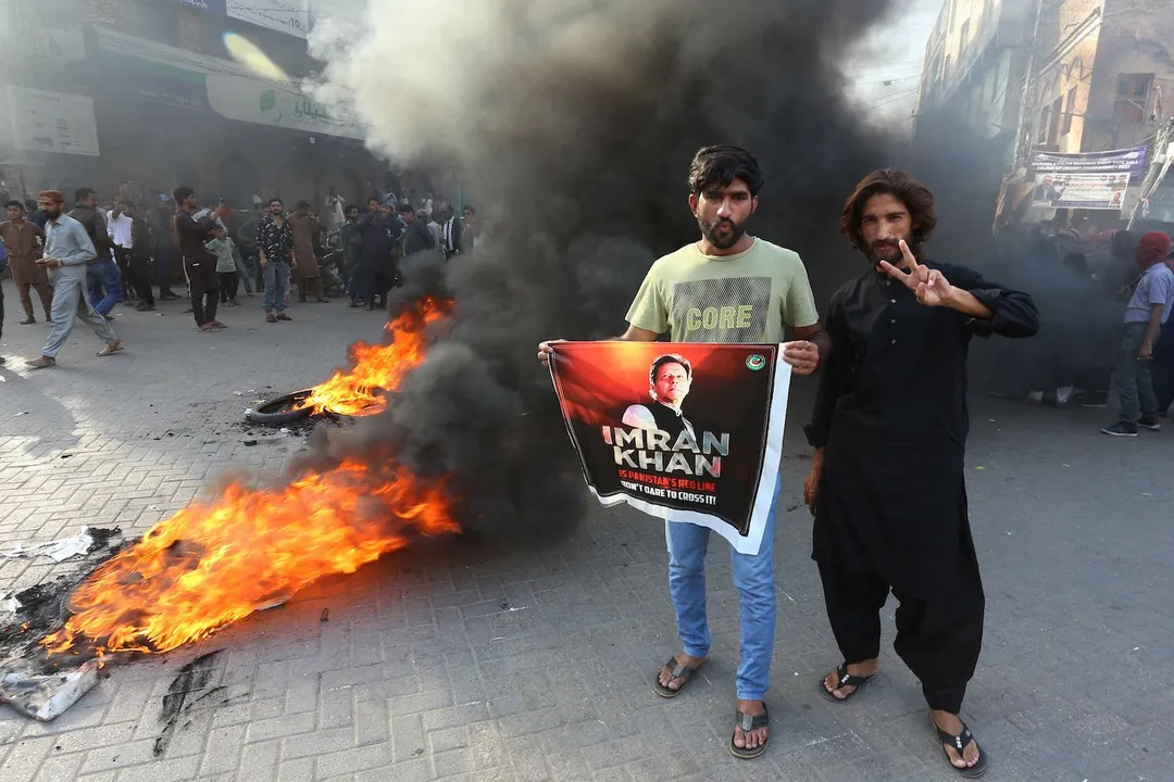  Pakistan Tehreek-e-Insaf party activists and supporters of former Pakistan's Prime Minister Imran stand beside burning tyres as they block a road during a protest against the arrest of their leader in Hyderabad on May 9, 2023. Imran Khan was arrested on May 9, police said, during a court appearance for one of dozens of cases pending since he was booted from office last year. (Photo by Akram SHAHID / AFP) 