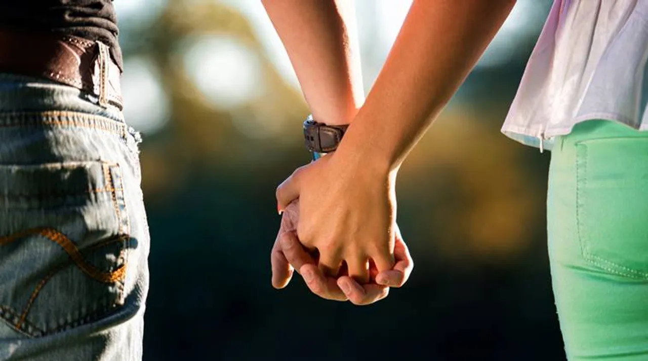  A Young Couple Holding Hands In The Sunset 