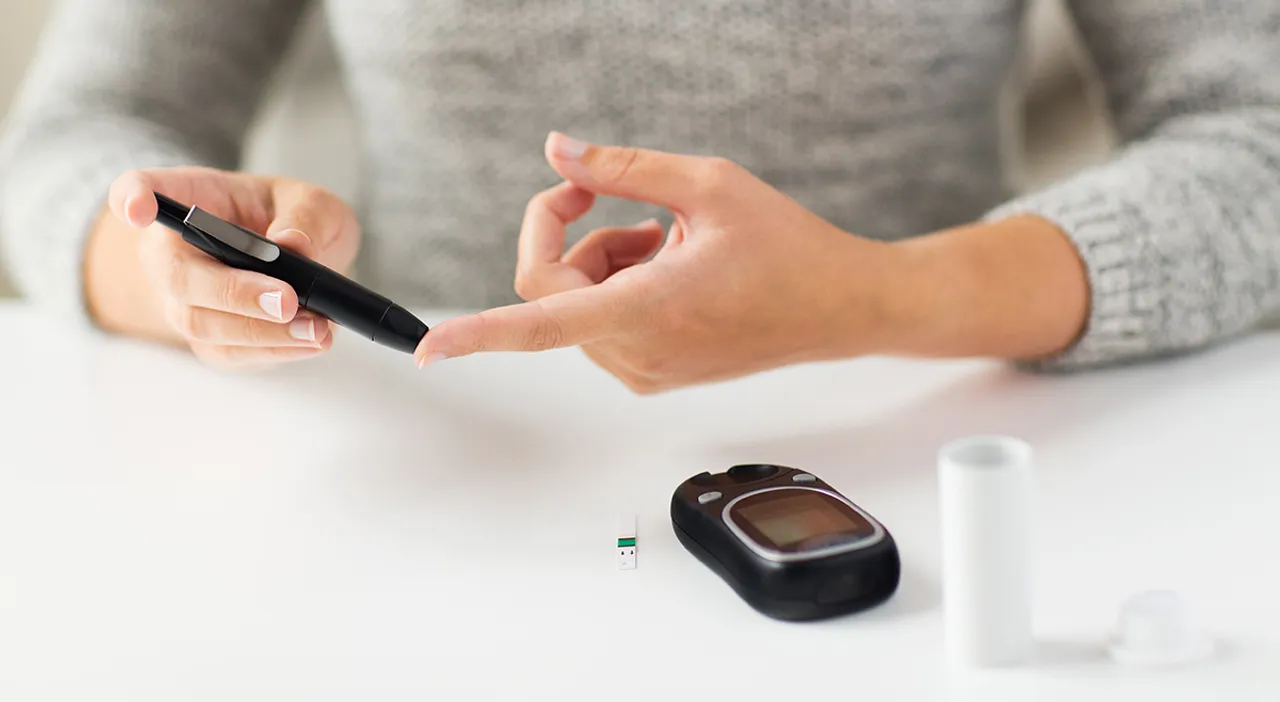  medicine, diabetes, glycemia, health care and people concept - close up of woman checking blood sugar level by glucometer at home 