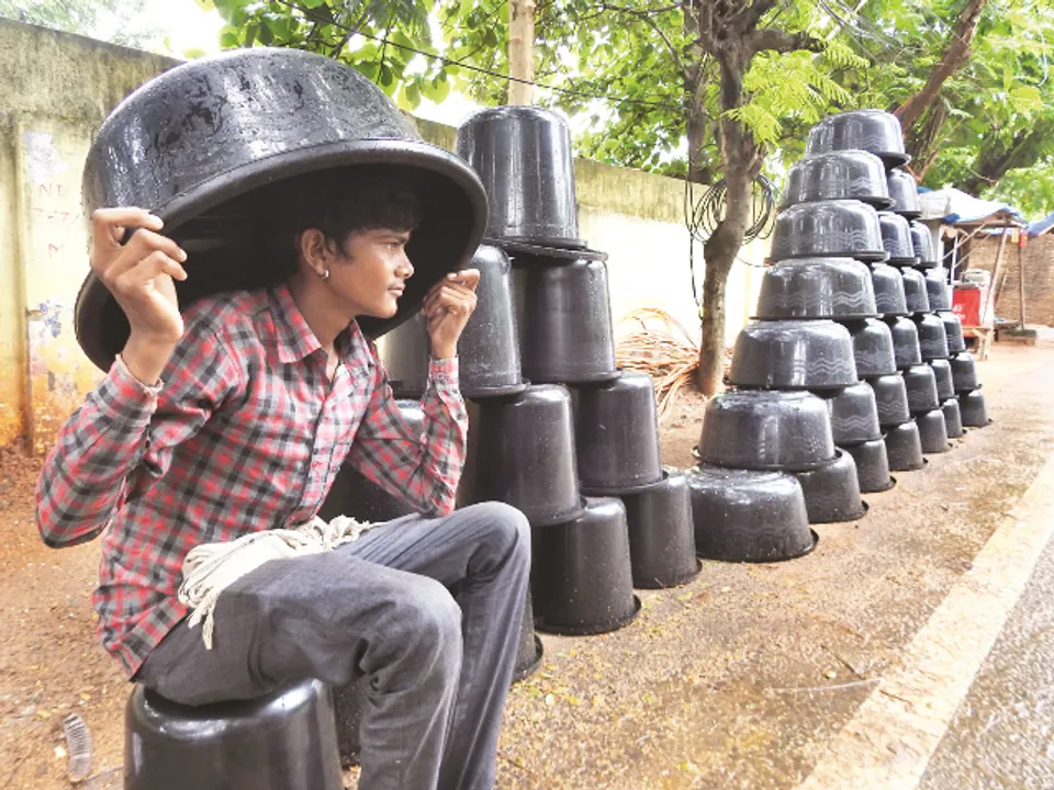  ରାସ୍ତାକଡ଼ରେ ଜଣେ ପ୍ଲାଷ୍ଟିକ ବ୍ୟବସାୟୀ ବର୍ଷାରୁ ରକ୍ଷା ପାଇବା ପାଇଁ ମୁଣ୍ଡ ଉପରେ ପ୍ଲାଷ୍ଟିକ କୁଣ୍ଡ ଘୋଡେଇ ବସିଛି।