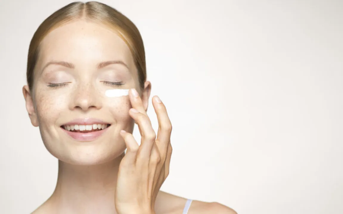  Young woman applying mositurizer under eye 