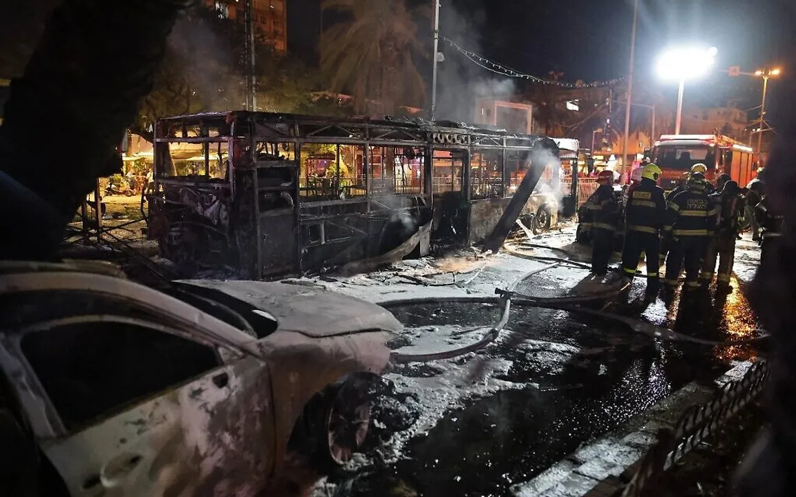  Israeli firefighters check out damaged vehicles in the Israeli town of Holon near Tel Aviv, on May 11, 2021, after rockets are launched towards Israel from the Gaza Strip controlled by the Palestinian Hamas movement. (Photo by ahmad gharabli / AFP) 