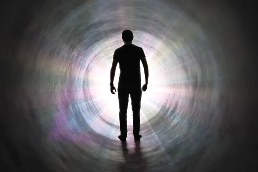  Life after death concept. Silhouette of man's soul is walking to bright light - rays of god inside tunnel. 