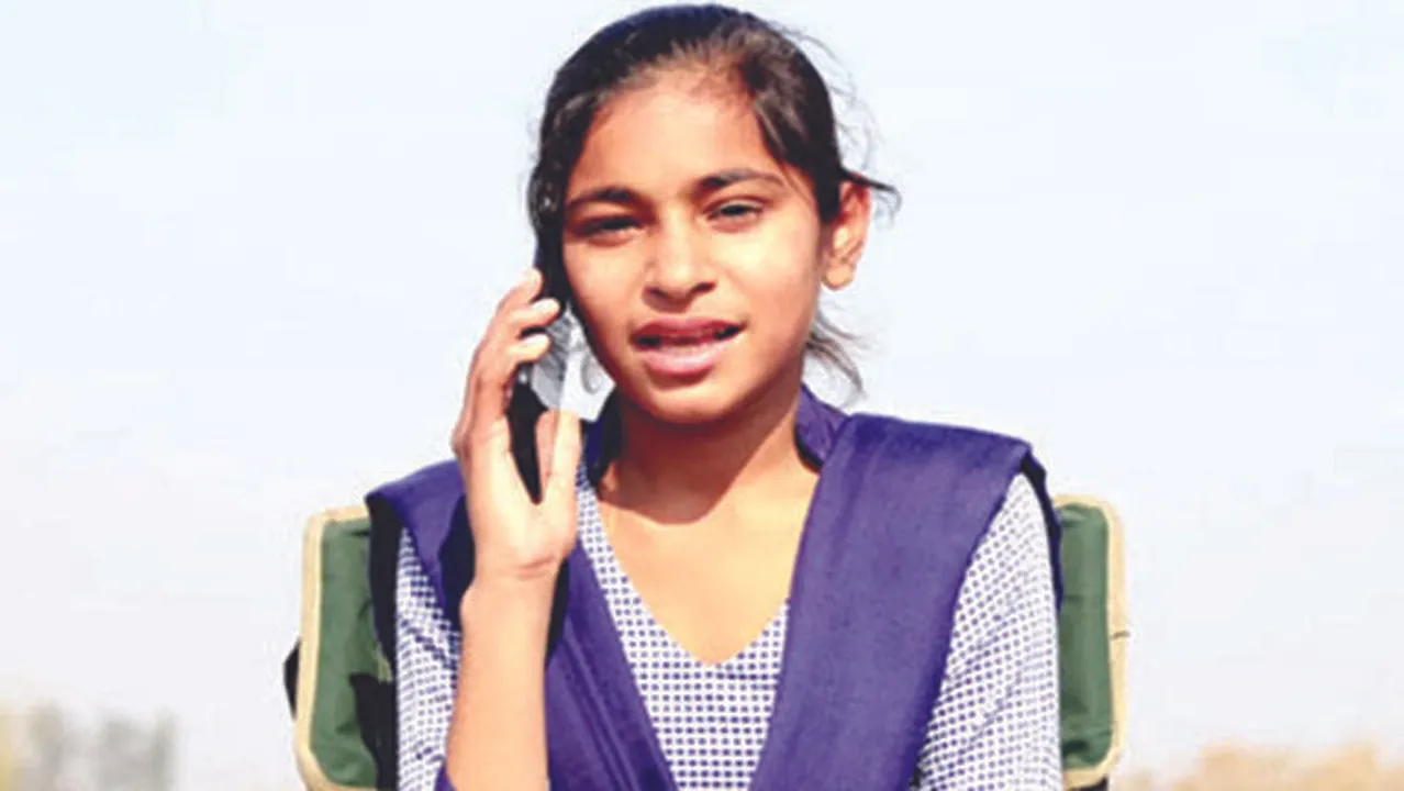  Teenager girl of Indian ethnicity sitting on the chair outdoor in nature talking on mobile phone. 