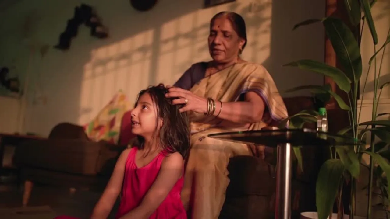 Grandmother putting hair oil in her grand daughters hair