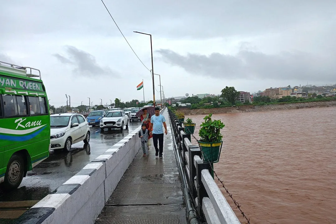  JAMMU, SEP 02 (UNI): People pass by from Tawi bridge as the water level of Tawi River increases following heavy rainfall, in Jammu on Tuesday. UNI Photo 105U 