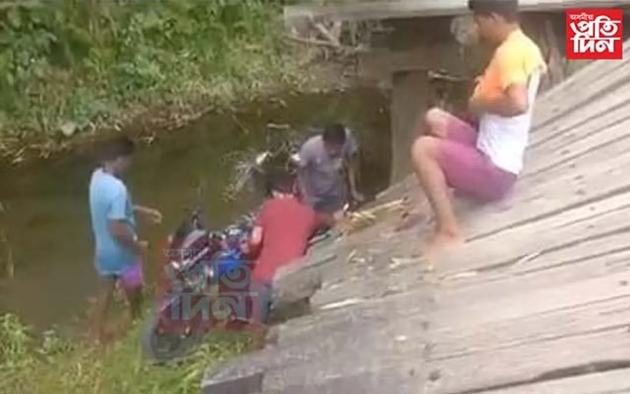 কাঠৰ দলং ভাগি তলত সৰি পৰিল মটৰচাইকেলসহ আৰোহী