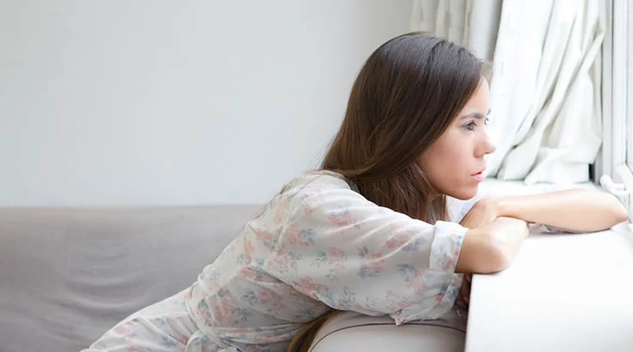 Young woman sitting alone looking out window