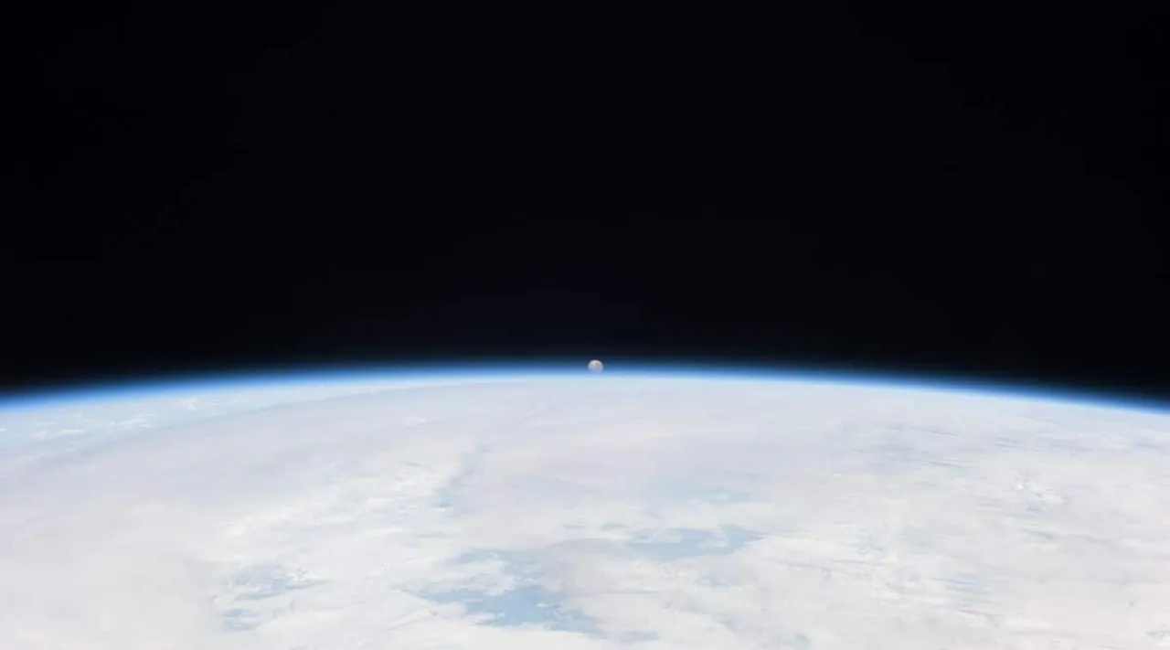 The Moon can be seen in the distance with the Earth in the foreground.