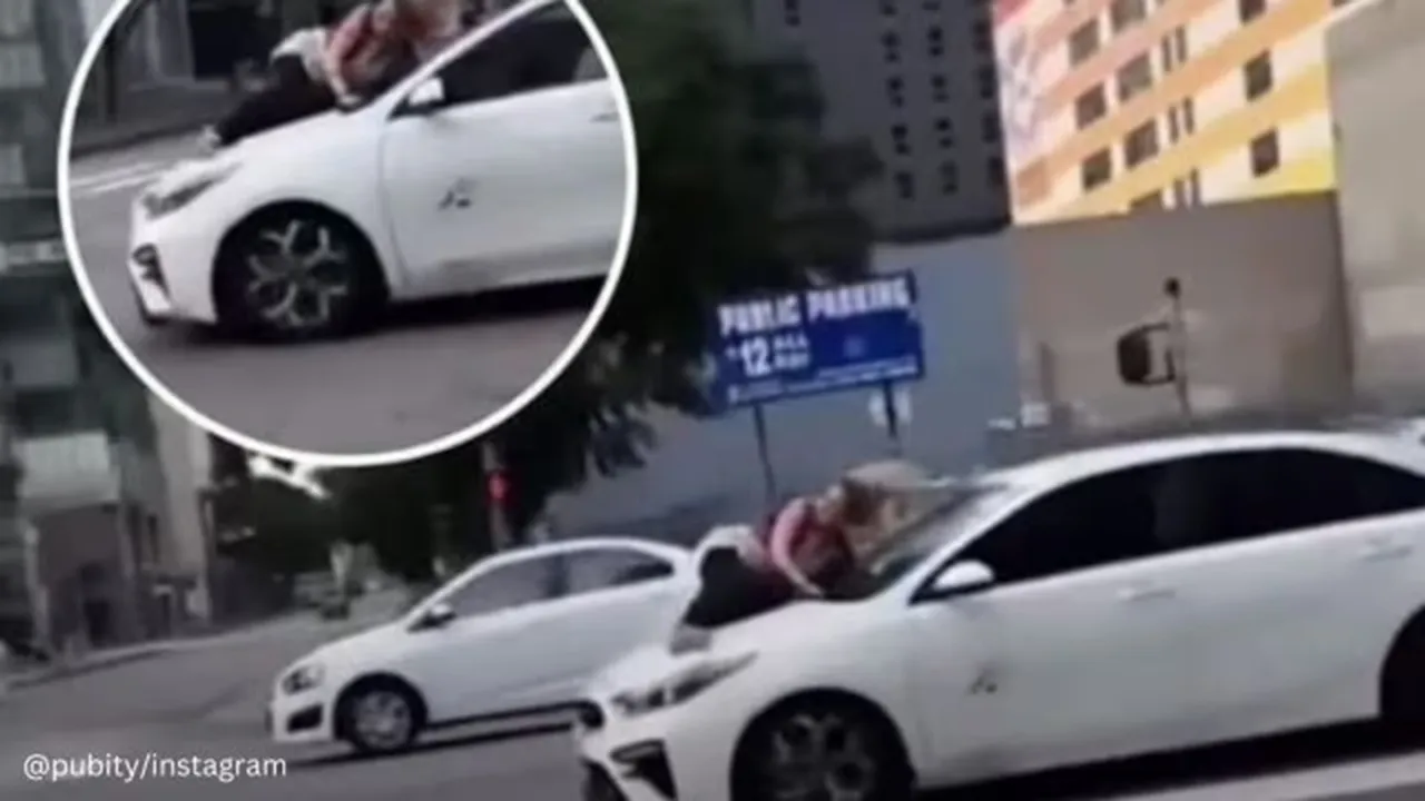 woman clinging to the hood of a moving vehicle