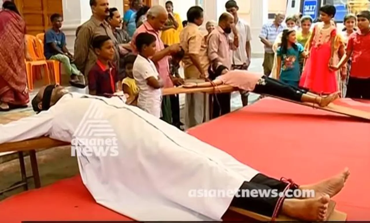 ഹർത്താലിനെതിരെ കണ്ണുകെട്ടി മുക്കാലിയിൽ കിടന്ന് വൈദികന്റെ പ്രതിഷേധം