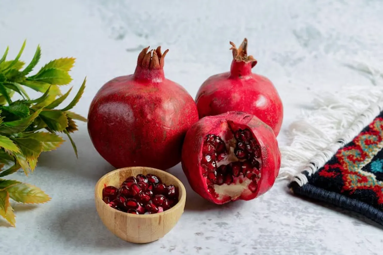 pomegranate-seeds-with-whole-sliced-pomegranates-grey-wall_114579-64640