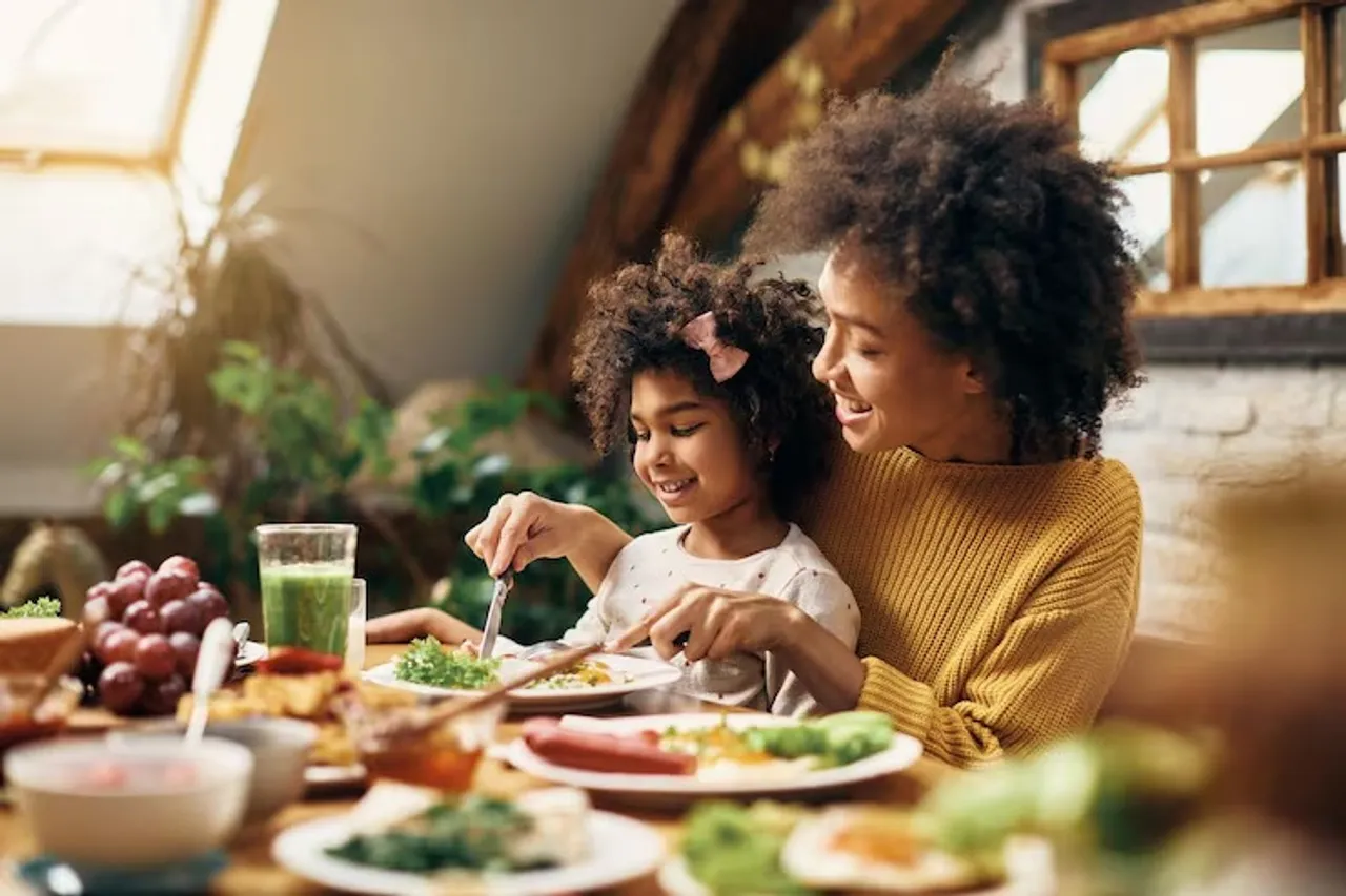 happy-african-american-mother-daughter-eating-dining-table_637285-12635