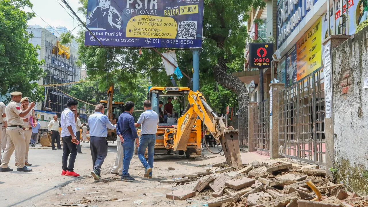 Police personnel guard as a bulldozer demolishes parts of the IAS coaching institute in Old Rajinder Nagar, where 3 students died due to drowning, in New Delhi, Monday, July 29, 2024.