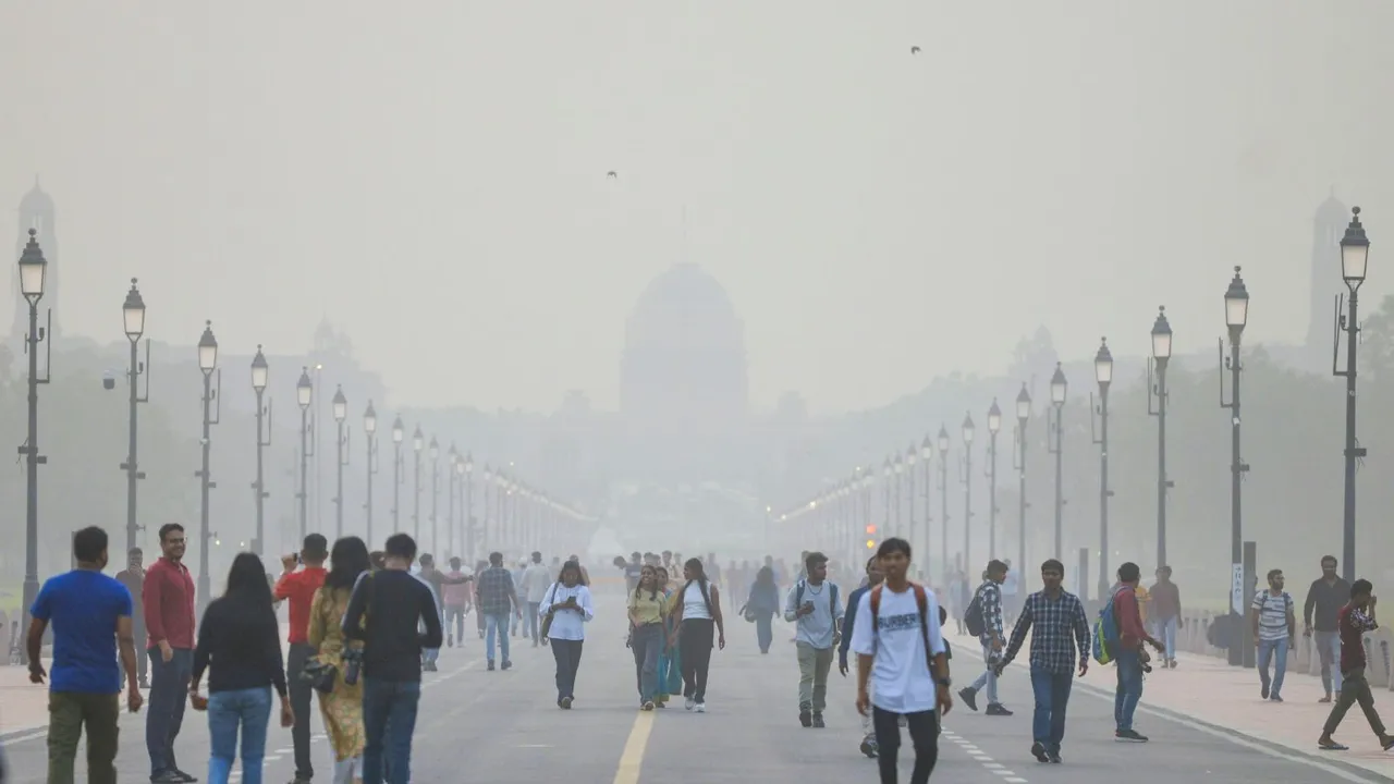 People walk on the Kartavya Path as smog shrouds Raisina hill, in New Delhi