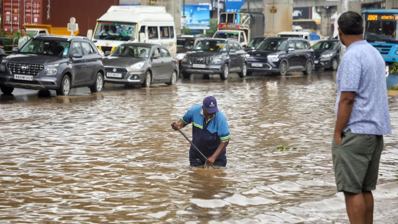 A Bruhat Bengaluru Mahanagara Palike (BBMP) worker clears the blocked drainage on a waterlogged road after rains, in Bengaluru, Sunday, Oct 20, 2024.
