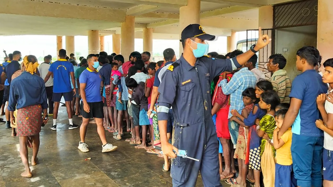 Affected people wait in queue as Navy personnel distribute relief materials in the aftermath of cyclone 'Dana', at an affected village in Kendrapara district of Odisha, Saturday, Oct 26, 2024.