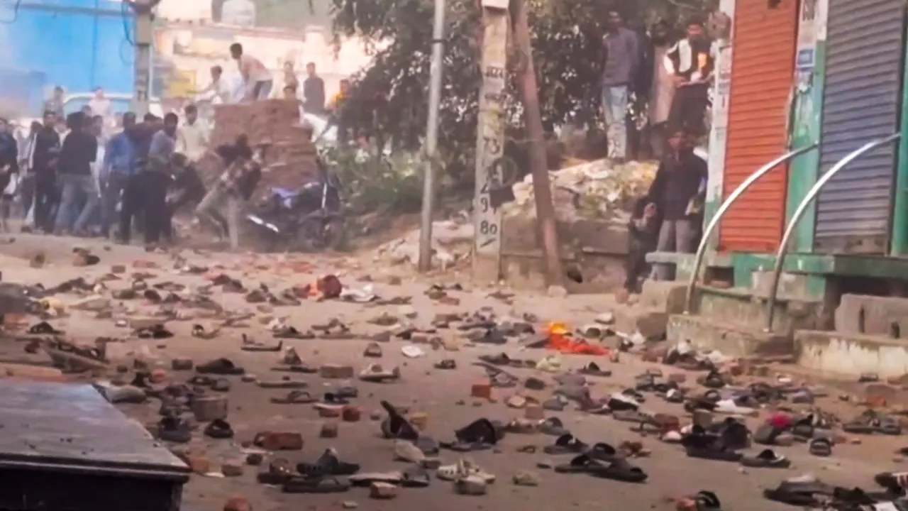 People and security personnel are seen standing near stones after locals clashed with personnel of the force during a second survey of the Jama Masjid, claimed to be originally the site of an ancient Hindu temple, in Sambhal, Sunday, Nov. 24, 2024