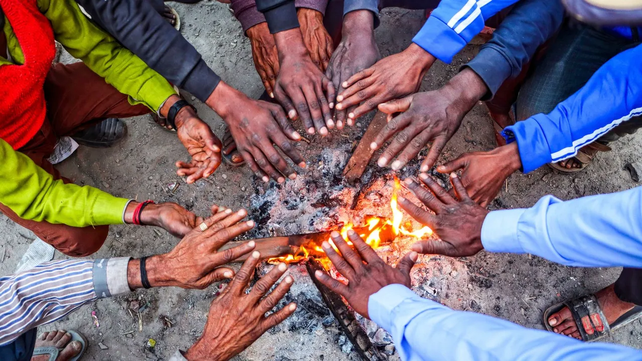 People sit around a bonfire to warm themselves during a cold winter evening