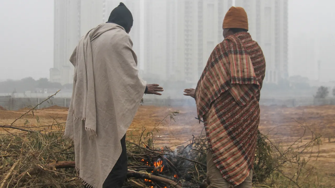 People stand near a bonfire to warm themselves on a cold winter day in Gurugram on Tuesday, Jan. 7, 2025.