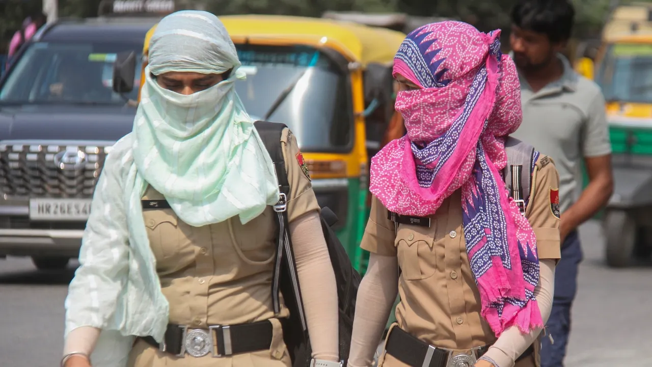 Women police personnel protect themselves from the sun on a hot summer day in Gurugram on Wednesday, April 16, 2025.