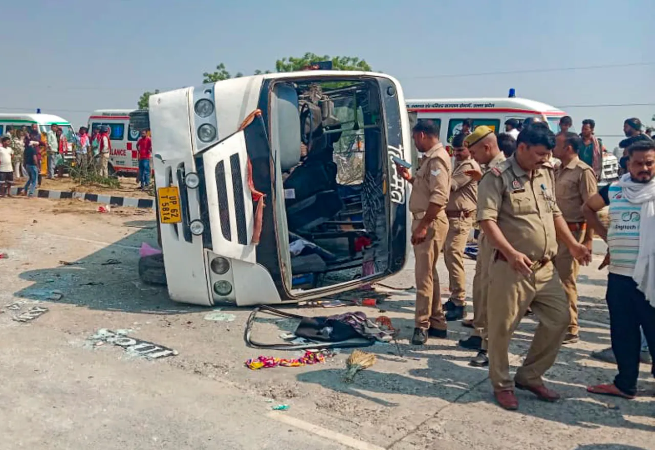 Police personnel and others stand near an overturned vehicle after an accident, in Jaunpur, Uttar Pradesh.
