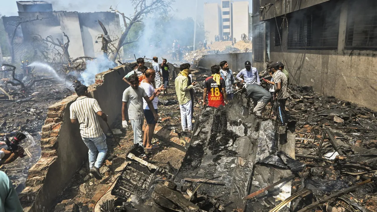 People stand near the debris of the Air India plane that crashed moments after taking off from the airport, in Ahmedabad, Thursday, June 12, 2025. The London-bound plane was carrying 242 passengers.