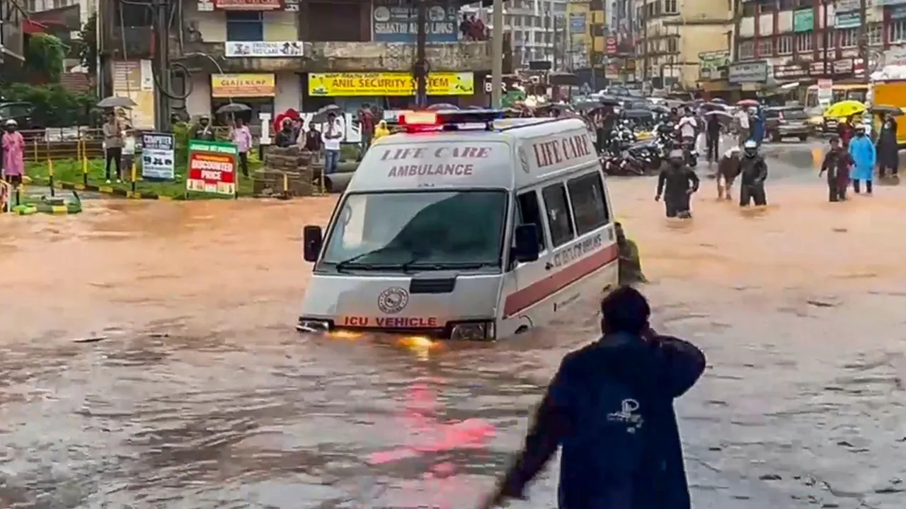 People push an ambulance while wading through a waterlogged road amid rainfall, in Mangaluru, Karnataka.