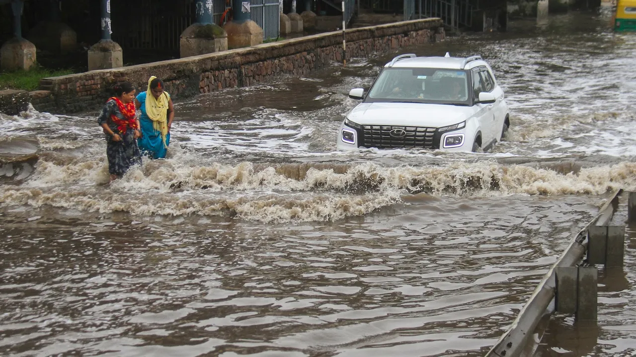 Commuters make their way through the waterlogged service road along the Delhi-Gurugram Expressway after heavy rainfall, in Gurugram, Wednesday, July 9, 2025.