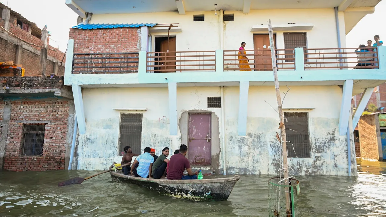 People use a boat to cross an area inundated due to the swollen Ganga river during the monsoon season, at Chhota Baghara in Prayagraj, Thursday, Aug. 28, 2025.