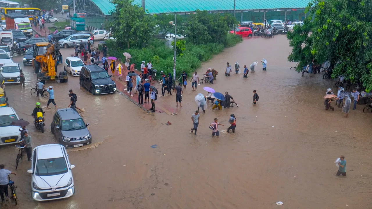 Commuters make their way through a waterlogged road amid rainfall, in Gurugram, Monday, Sept. 1, 2025.