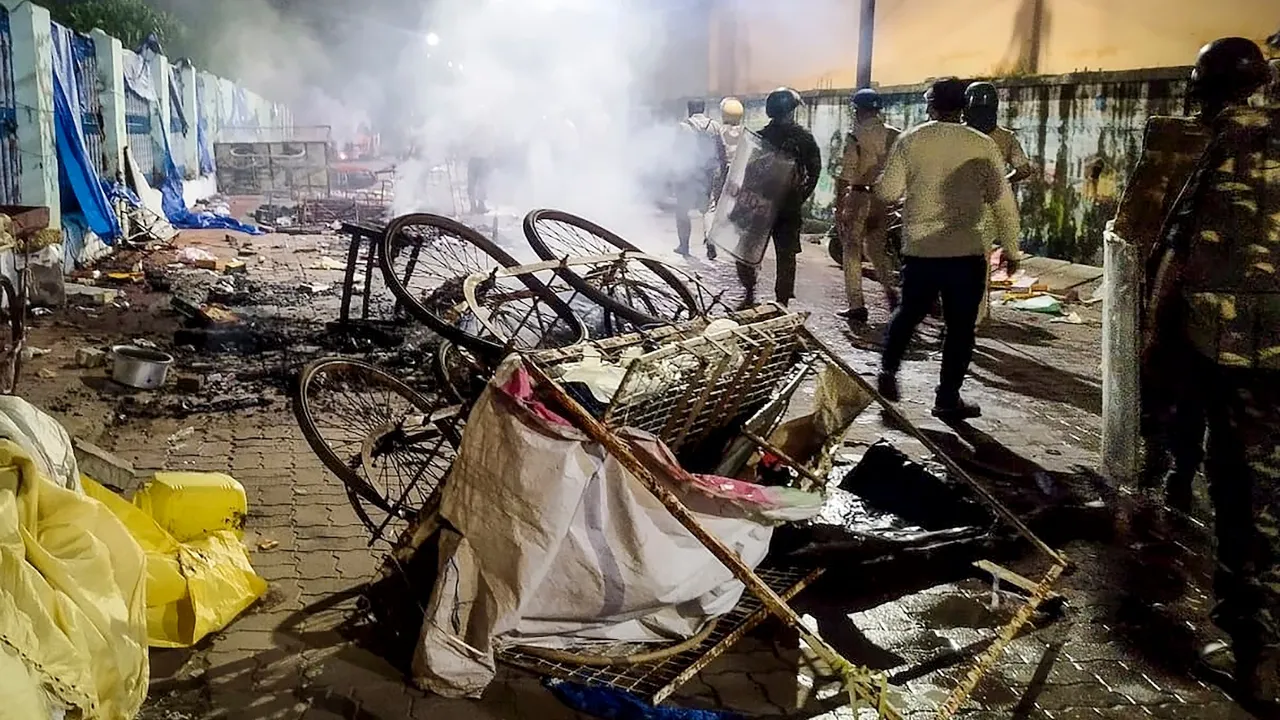 Smoke billows from charred remains of a cart as police and security personnel keep a vigil after fresh incidents of violence linked to a group clash two days ago during a Durga idol immersion procession, in Cuttack, Odisha, Sunday, Oct. 5, 2025.