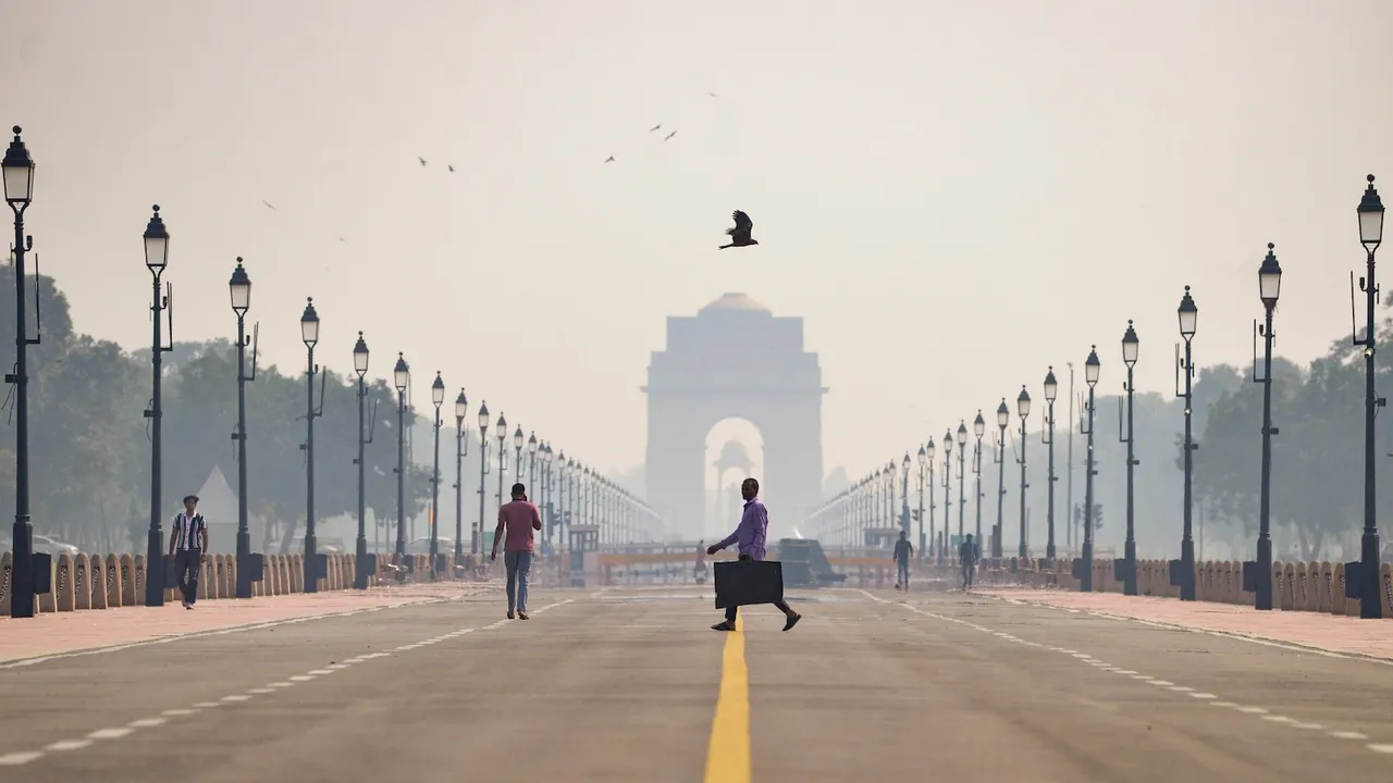People walk along a road amid low visibility caused by worsening air quality, with India Gate shrouded in haze in the backdrop, in New Delhi, Friday, Oct. 17, 2025.