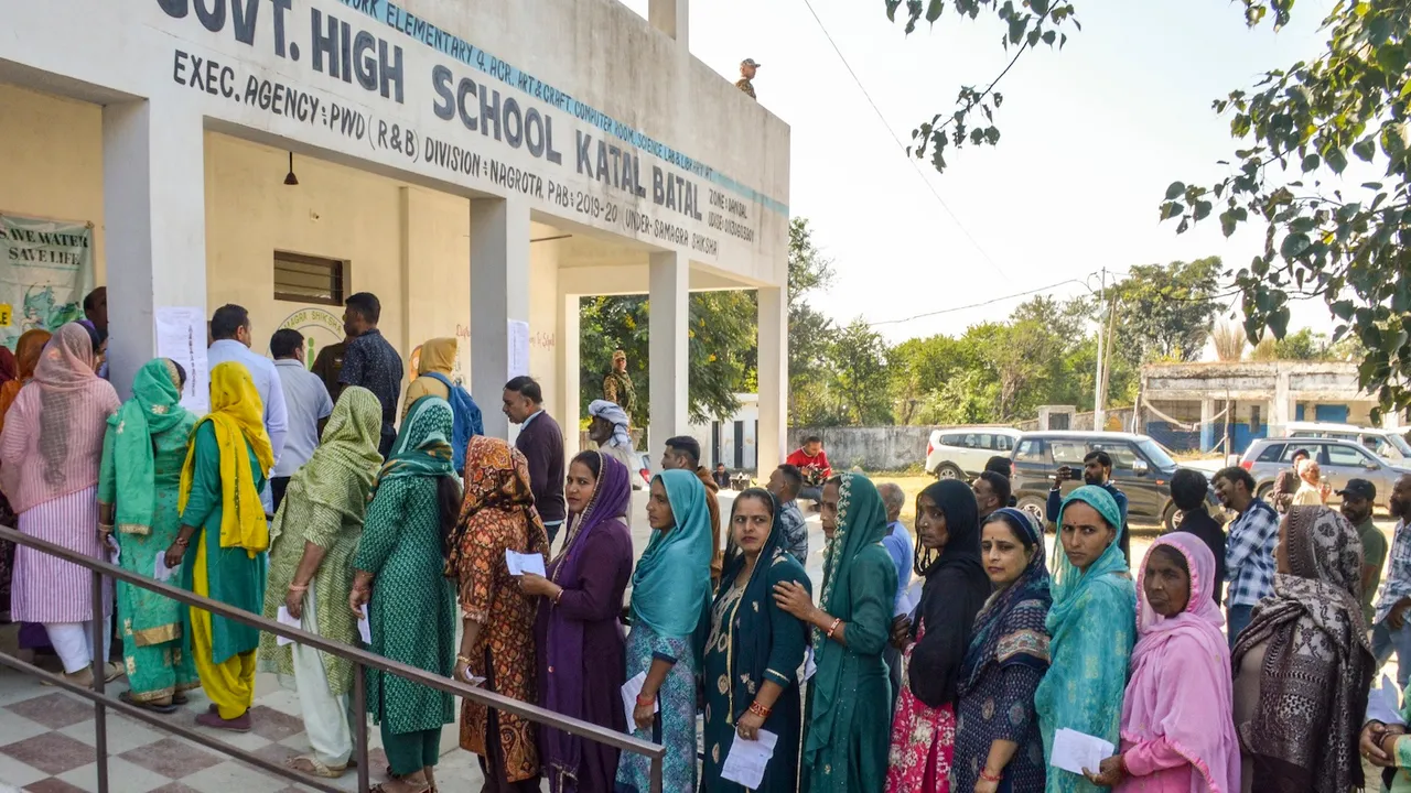 Voters wait in a queue to cast their votes at a polling station during the Nagrota assembly constituency bypoll, in Jammu district, Tuesday, Nov. 11, 2025.