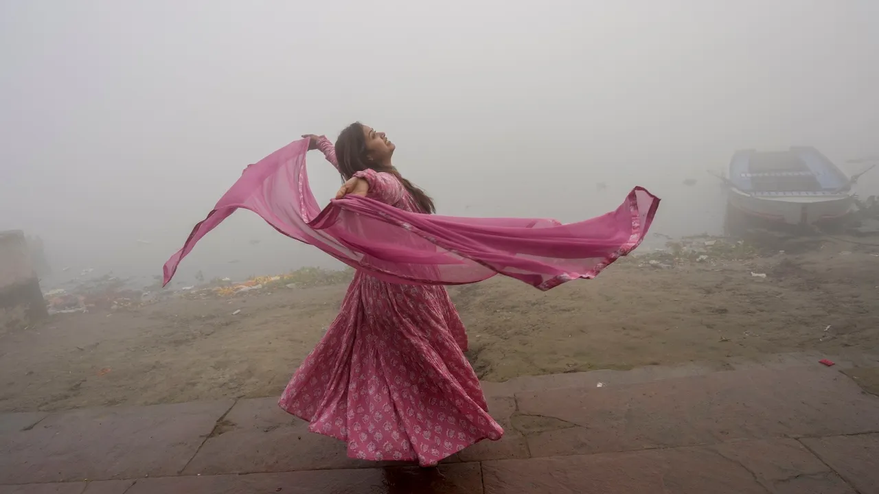 A visitor poses for photographs at the bank of the Yamuna river amid low visibility due to a layer of smog, in New Delhi, Sunday, Dec. 14, 2025.
