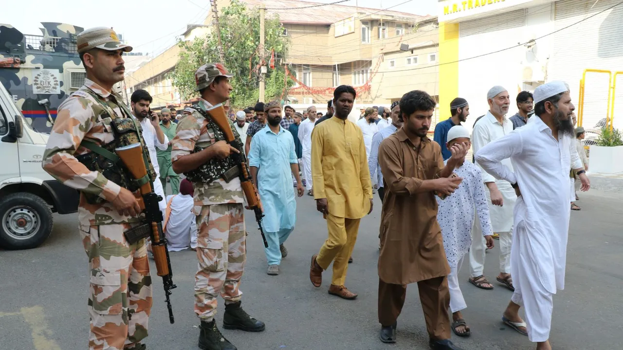 Devotees pass by security personnel standing guard during the Eid al-Adha celebration, in Jammu, Monday, June 17, 2024.