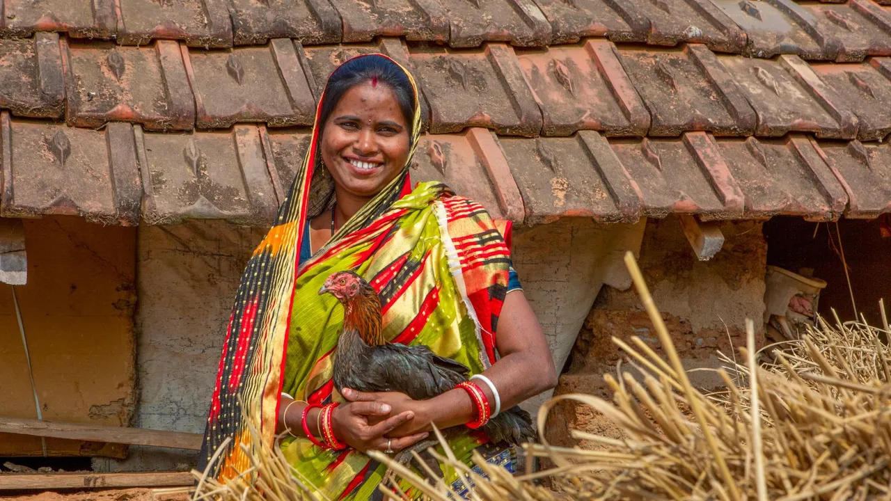 Parbati Mohanta, 33, stands in front of her home holding a chicken in Tentala village of Mayurbhanj district, India, Dec. 22, 2023
