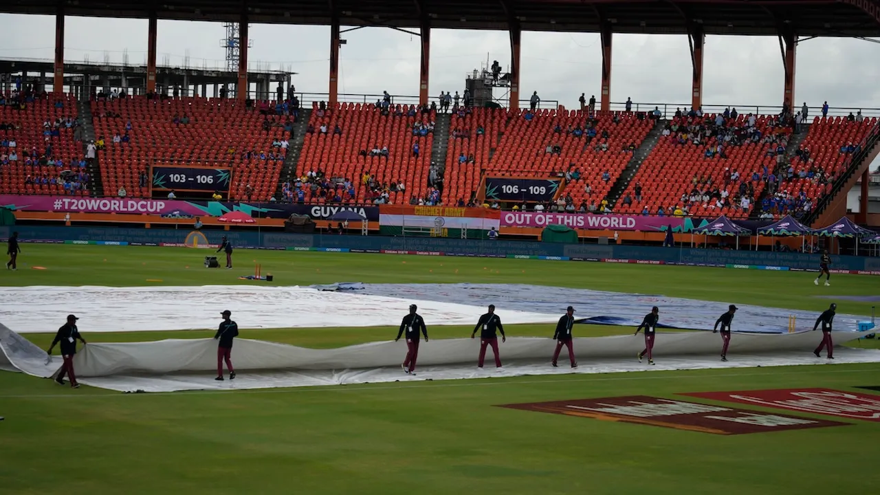 Groundsmen move the covers after wet outfield delayed the toss for the ICC Men's T20 World Cup second semifinal cricket match between England and India at the Guyana National Stadium in Providence, Guyana, Thursday, June 27, 2024.