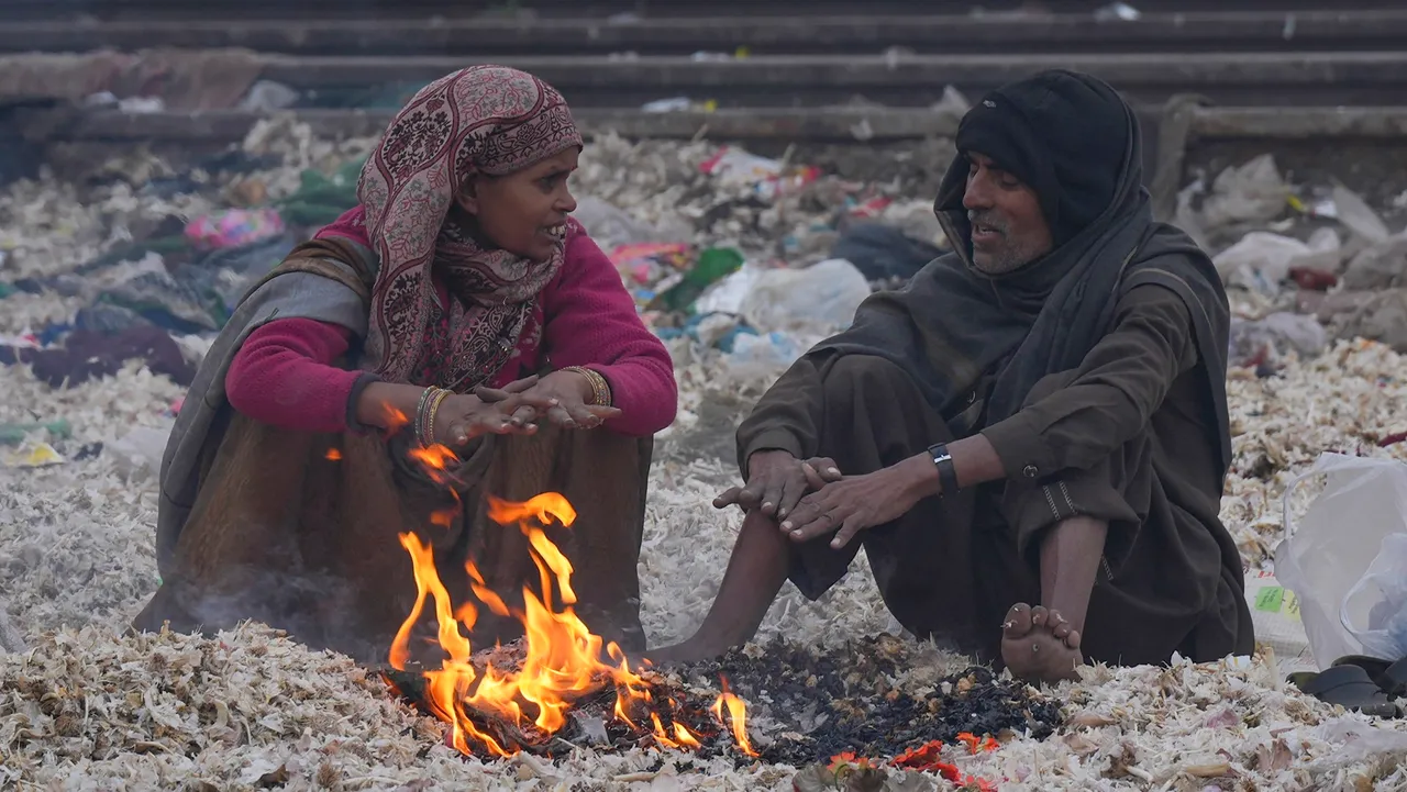 People warm themselves with a bonfire during a cold and foggy winter morning