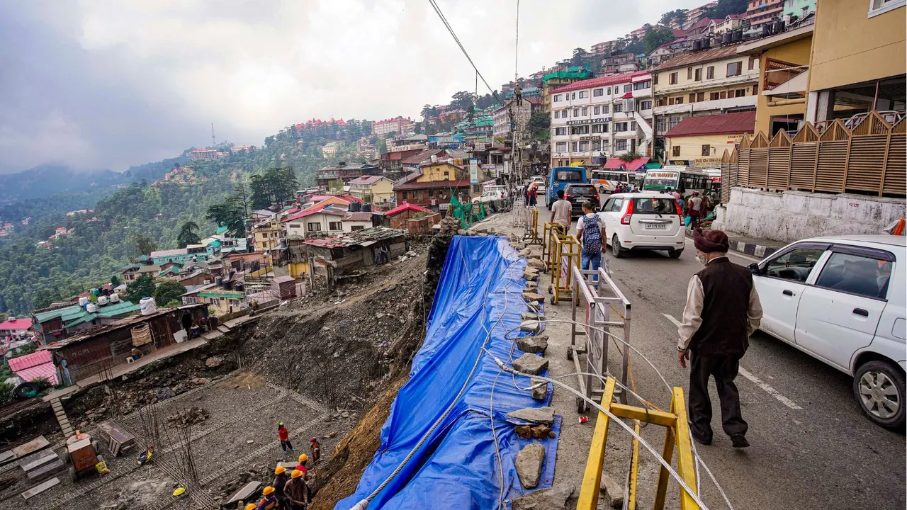 Vehicles move past a damaged section of the Circular Road following a landslide, in Shimla