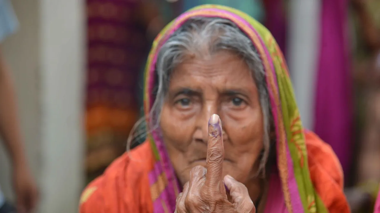 An elderly voter shows her finger marked with indelible ink after casting her vote as others wait in a queue to vote for the fifth phase of Lok Sabha elections, in Hajipur, Monday, May 20, 2024