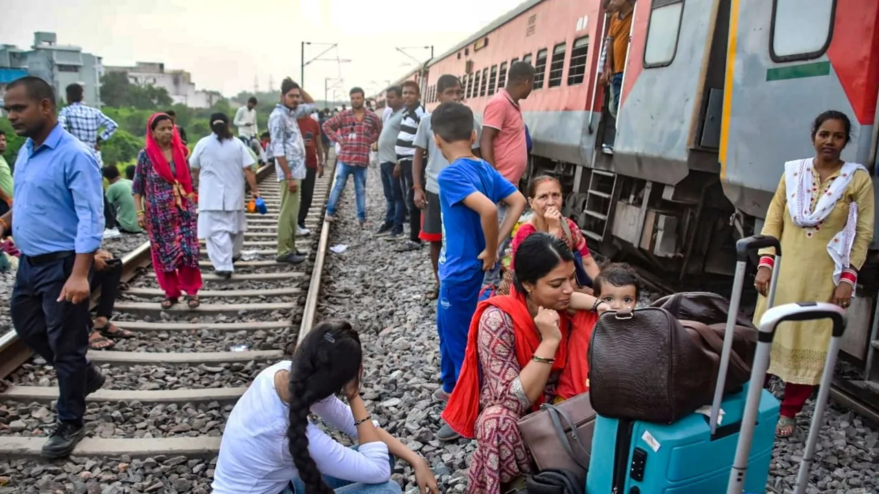 Passengers sit outside the Sabarmati Express after twenty coaches of the train derailed near Govindpuri station, in Kanpur, Saturday, Aug. 17, 2024.